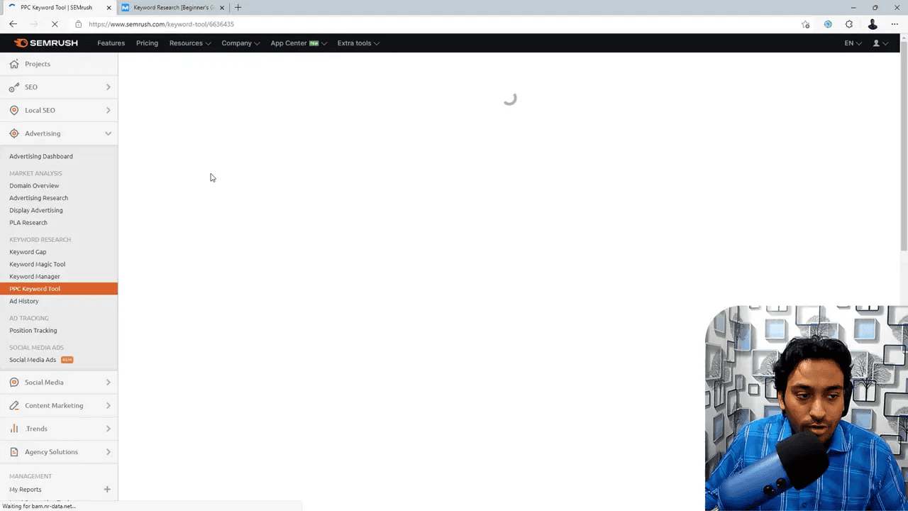 Semrush PPC Keyword Tool screen with the left navigation highlighting 'PPC Keyword Tool', a central loading spinner and a presenter video overlay in the bottom-right.
